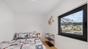 Ein Schlafzimmer mit einem Bett, einem Fenster und einem Regal.