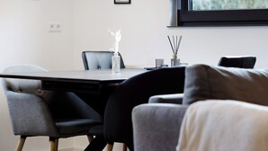 Ein modernes Zimmer mit Esstisch, Stühlen, einer Couch und einem Fenster.