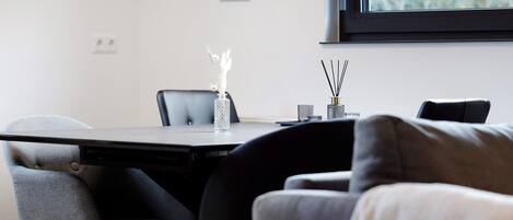 A modern room with a dining table, chairs, a sofa, and a window.