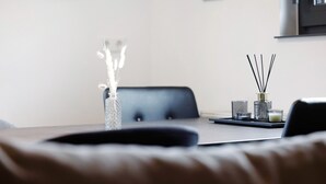 Ein moderner Essbereich mit Tisch, Stühlen, einer Vase mit getrockneten Blumen und einem Kerzenständer.
