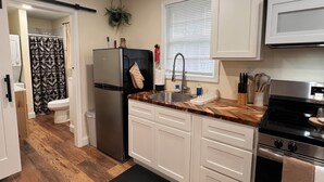 Una cocina moderna con armarios blancos, un refrigerador de acero inoxidable, un horno empotrado y un microondas.