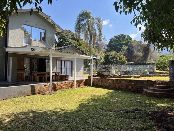 A house with a covered patio, a stone wall, and a grassy yard.