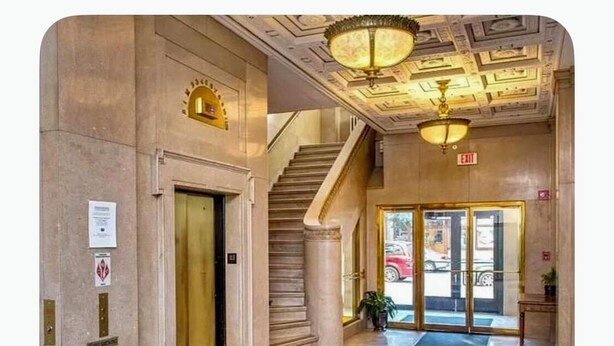 Un hall d’entrée avec un sol en marbre, un escalier et un espace de réception doté d’une porte en verre.