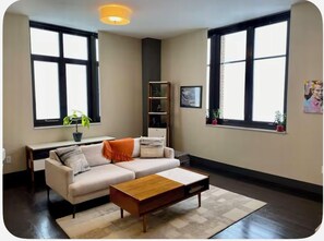 Una sala de estar moderna con un sofá, una mesa de centro y ventanas amplias.