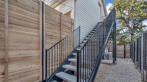 Eine Holzfassade, eine Treppe mit Metallgeländern und ein Kiesweg.