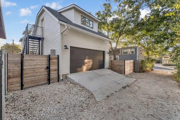 A single-story house with a garage, a wooden fence, and a gravel driveway.
