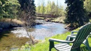 Jokirannalla oleva tuoli, taustalla puinen silta.
