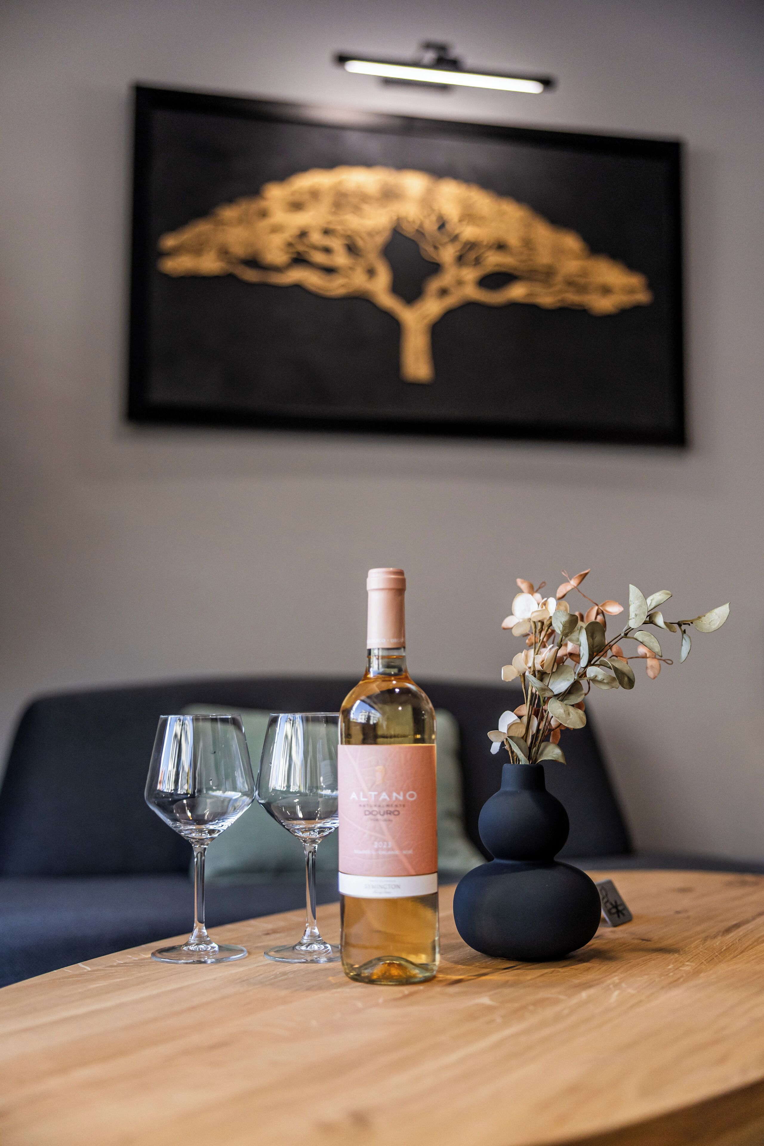 A table with a bottle of wine, two glasses, and a vase with flowers.