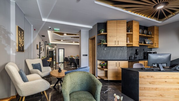 A modern hotel lobby with a reception desk, seating area, and a kitchen visible in the background. - Acacia Boutique Hotel (Sofia)