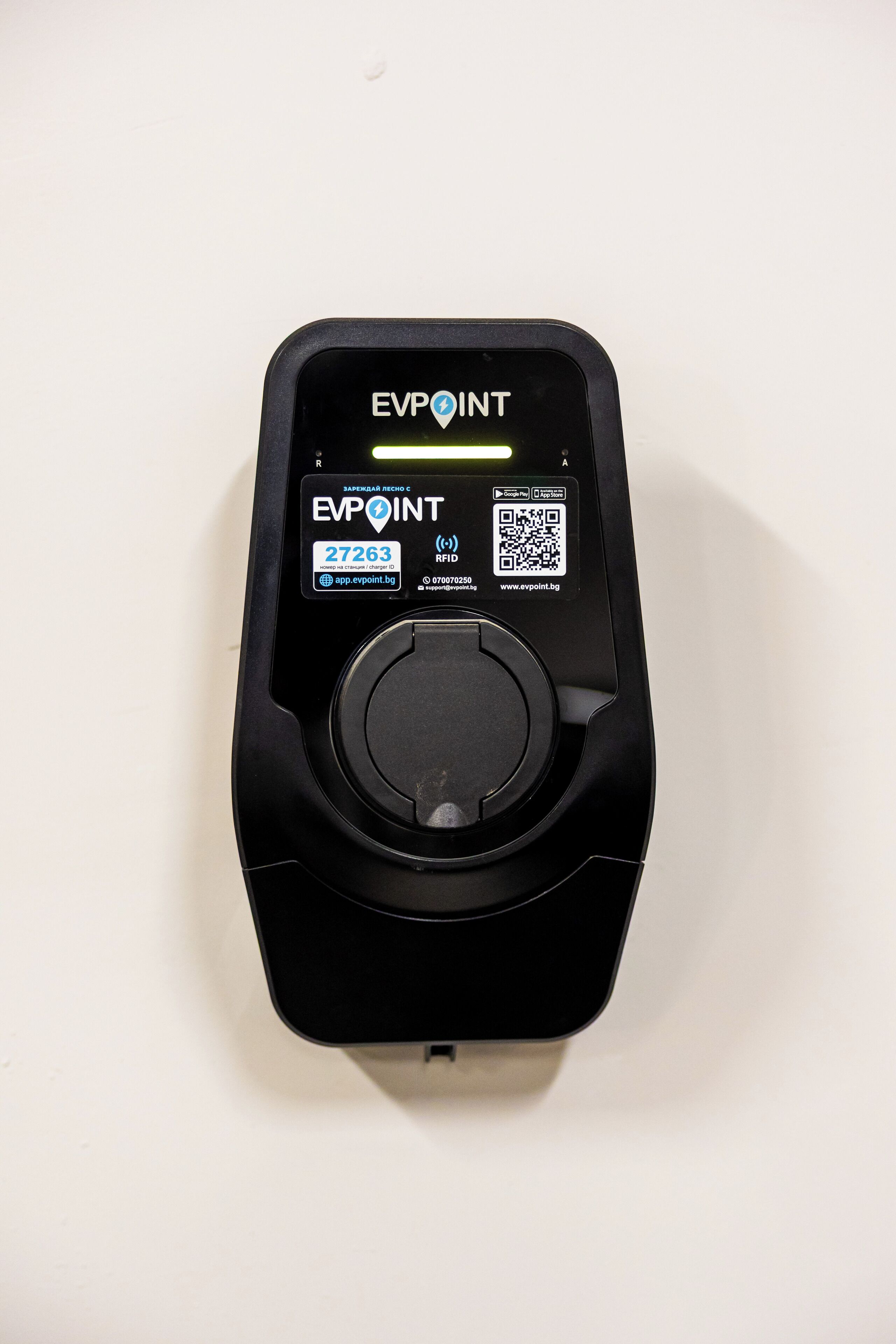Una estación de carga EVPOINT negra con un código QR, iconos de la tienda de aplicaciones y un identificador de cargador.