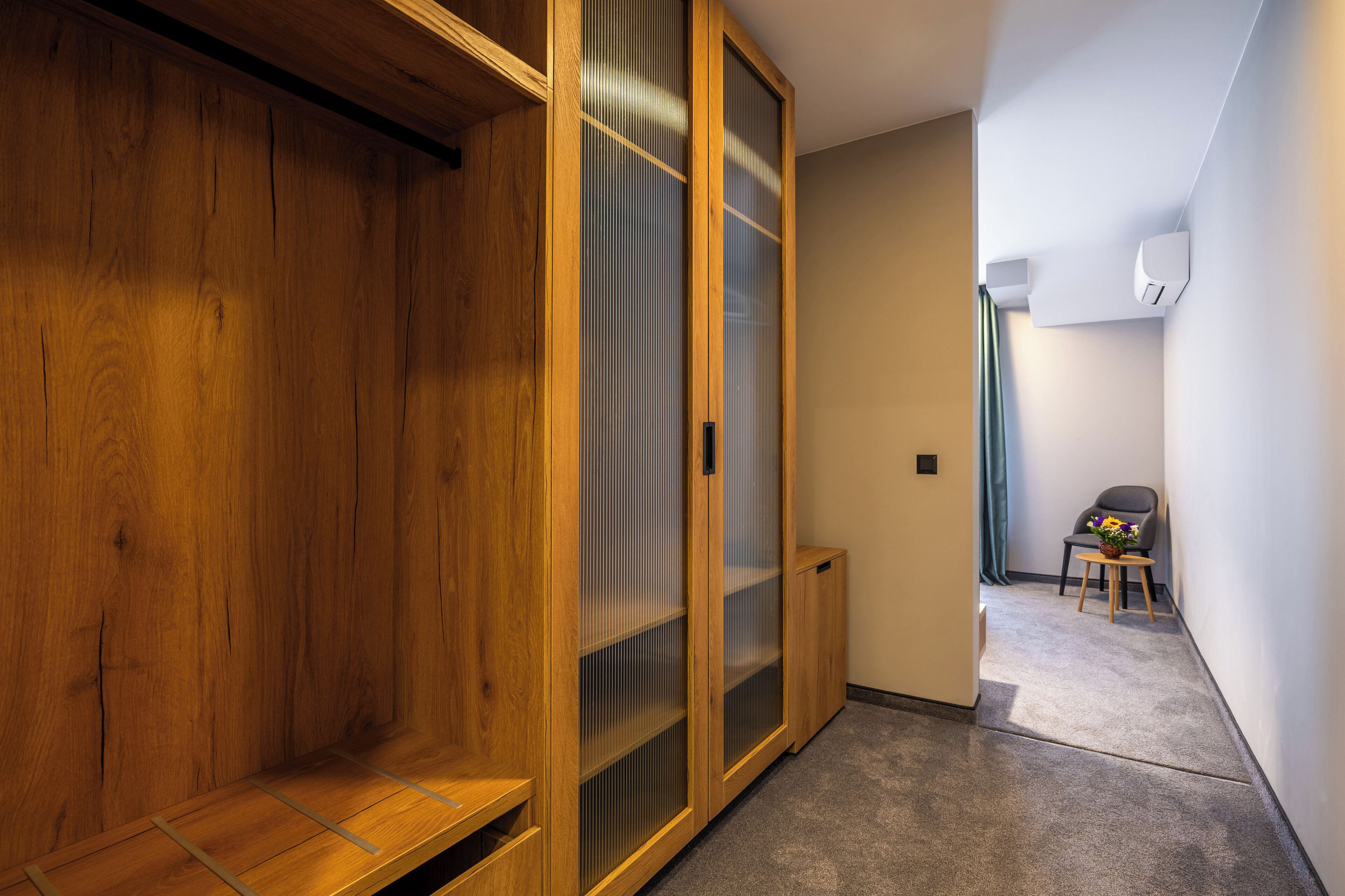 A hallway with wooden flooring, a sliding glass door, and a small table with flowers.