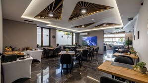 A modern dining area with a long table, multiple chairs, and a large screen. - Acacia Boutique Hotel (Sofia)