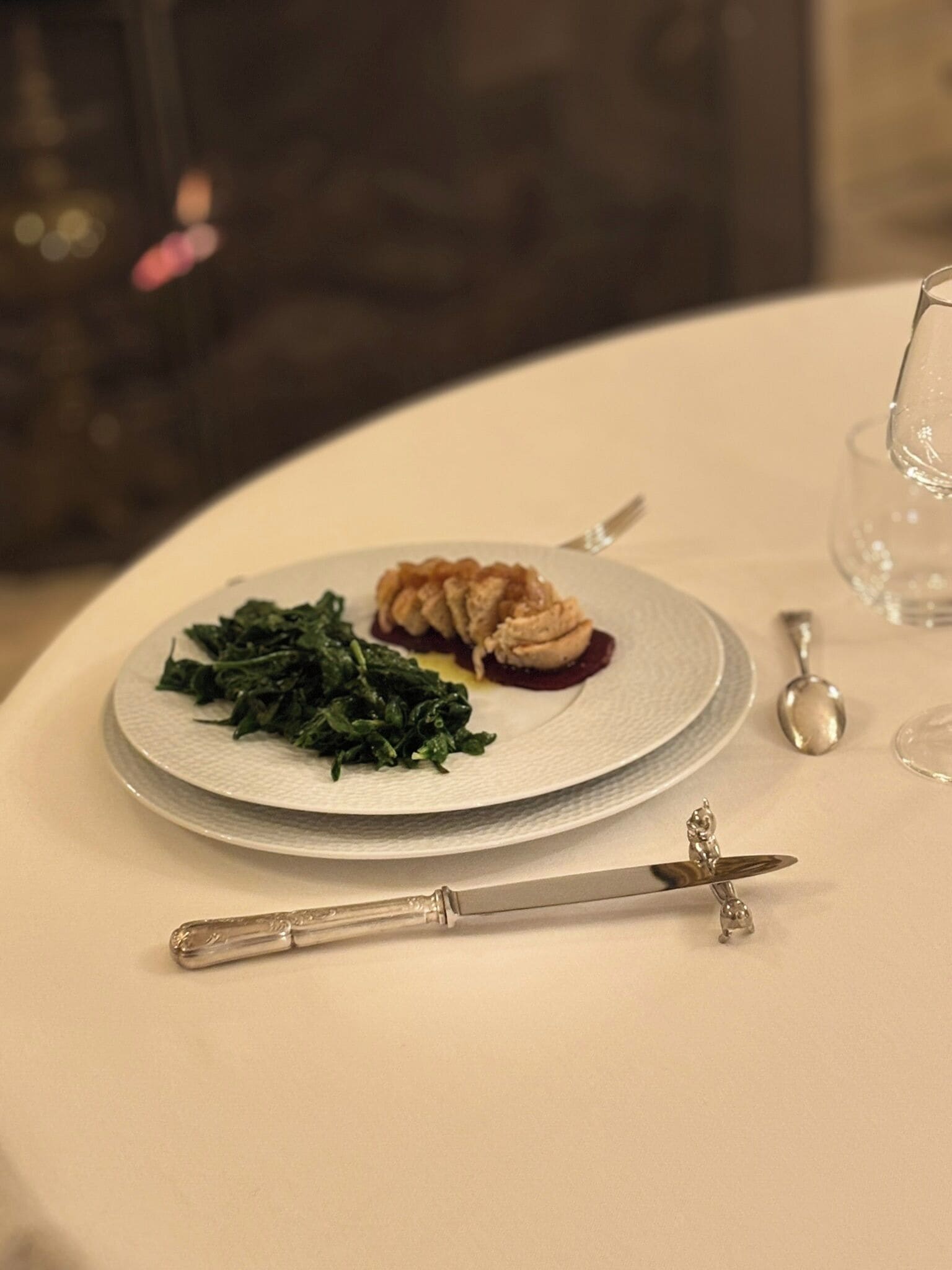 Un plato de comida con verduras y un guiso de carne, un cuchillo y una cuchara sobre una mesa.