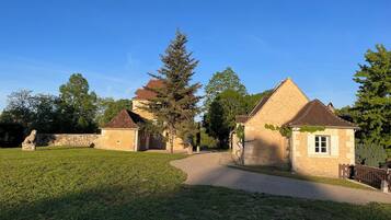 Un bâtiment en pierre avec un toit en tuiles, une pelouse verdoyante et une statue.