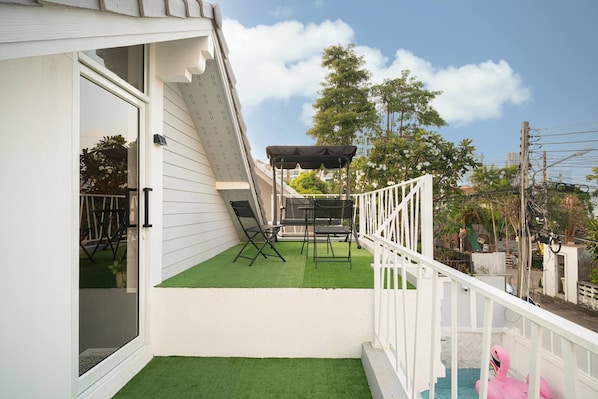 A balcony with artificial grass, a white railing, and a pink flamingo float.