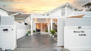Eine Villa mit überdachter Veranda, Blumentöpfen und einem Schild mit der Aufschrift 'Mohana Villa by MoMo'.