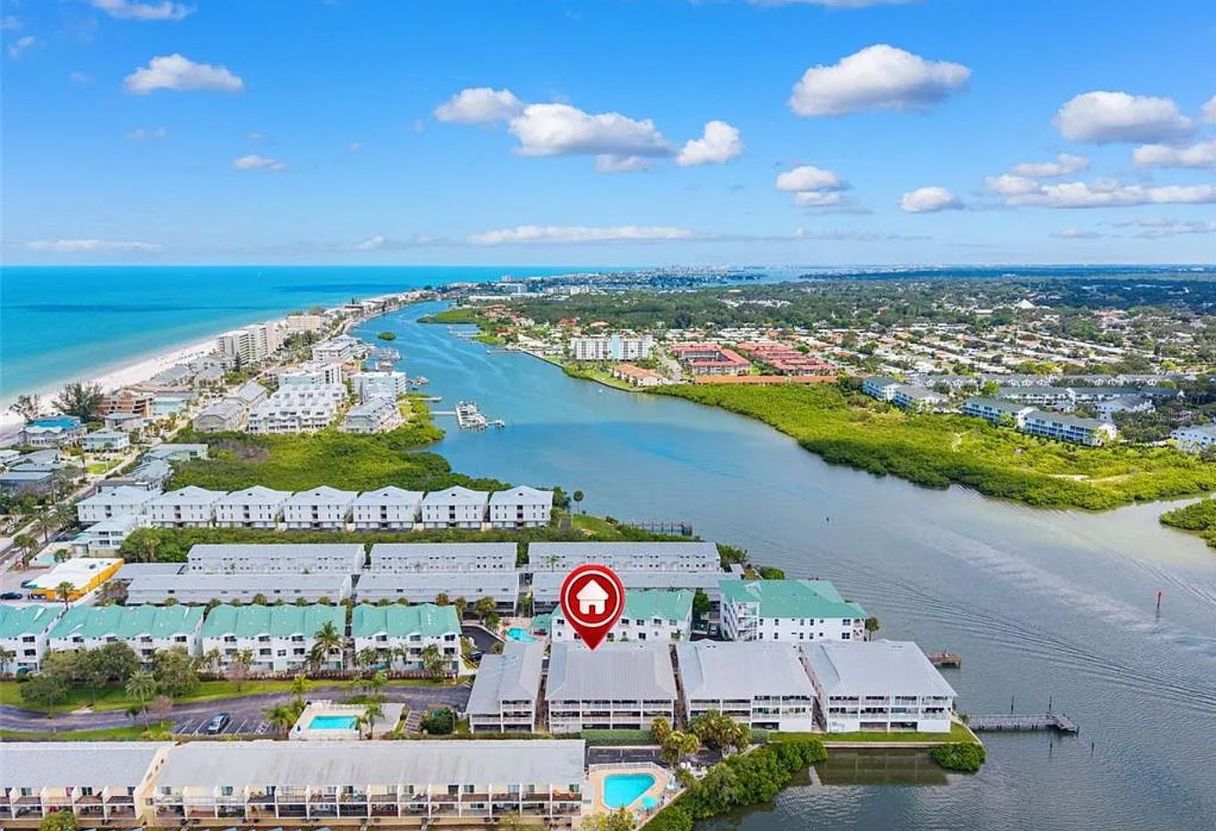 An aerial view of a coastal hotel area with multiple buildings, a river, and a beach.
