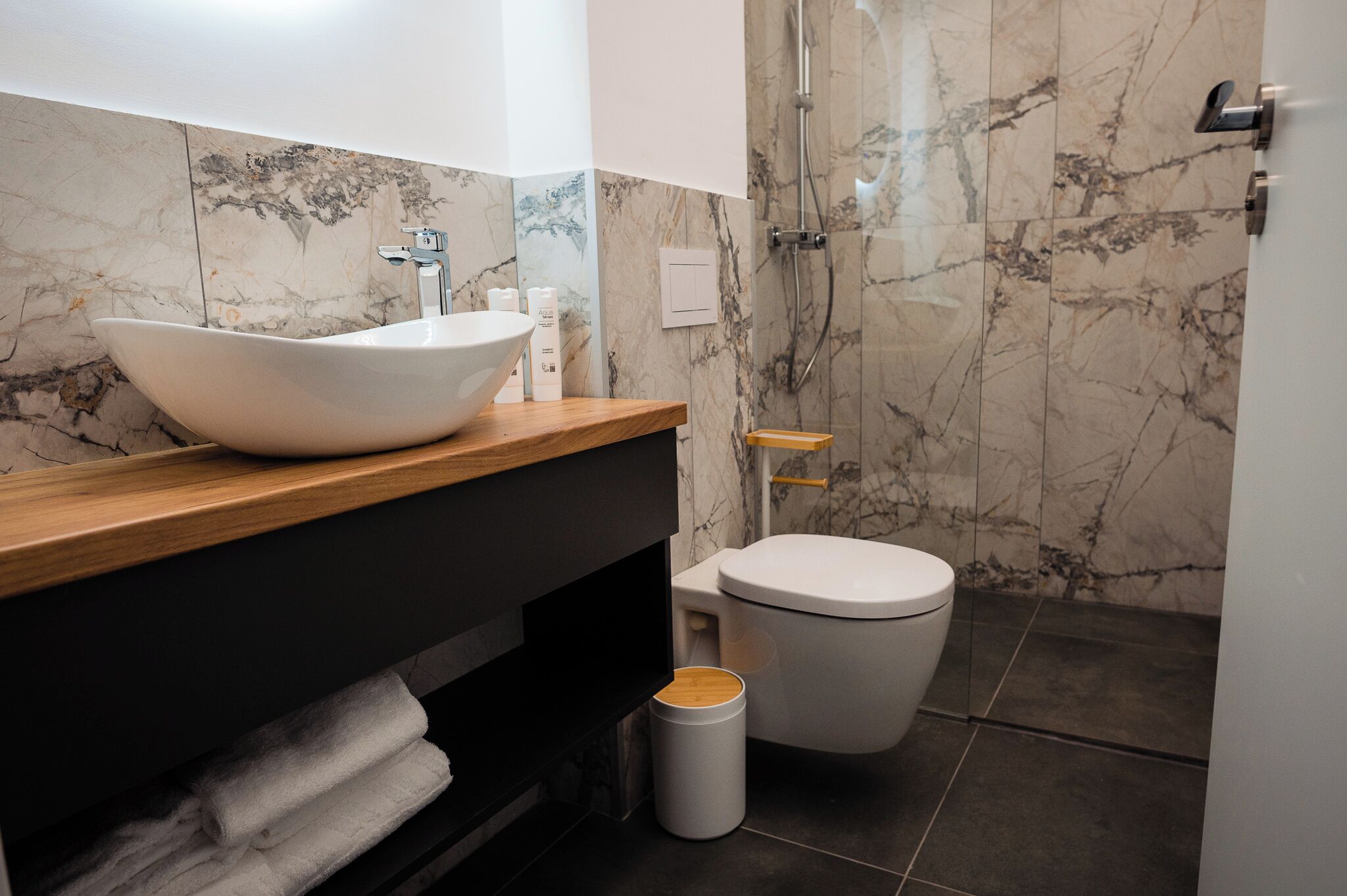 A modern bathroom with a large vessel sink, a toilet, and a shower area.