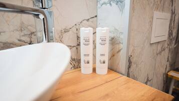 Un baño con pared de mármol, encimera de madera y dos botellas de jabón líquido y champú Aqua Senses.