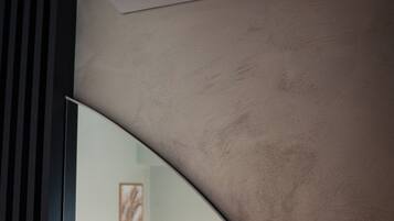 Una habitación moderna con cama, aire acondicionado instalado y una vista parcial de una pared con un cuadro enmarcado.