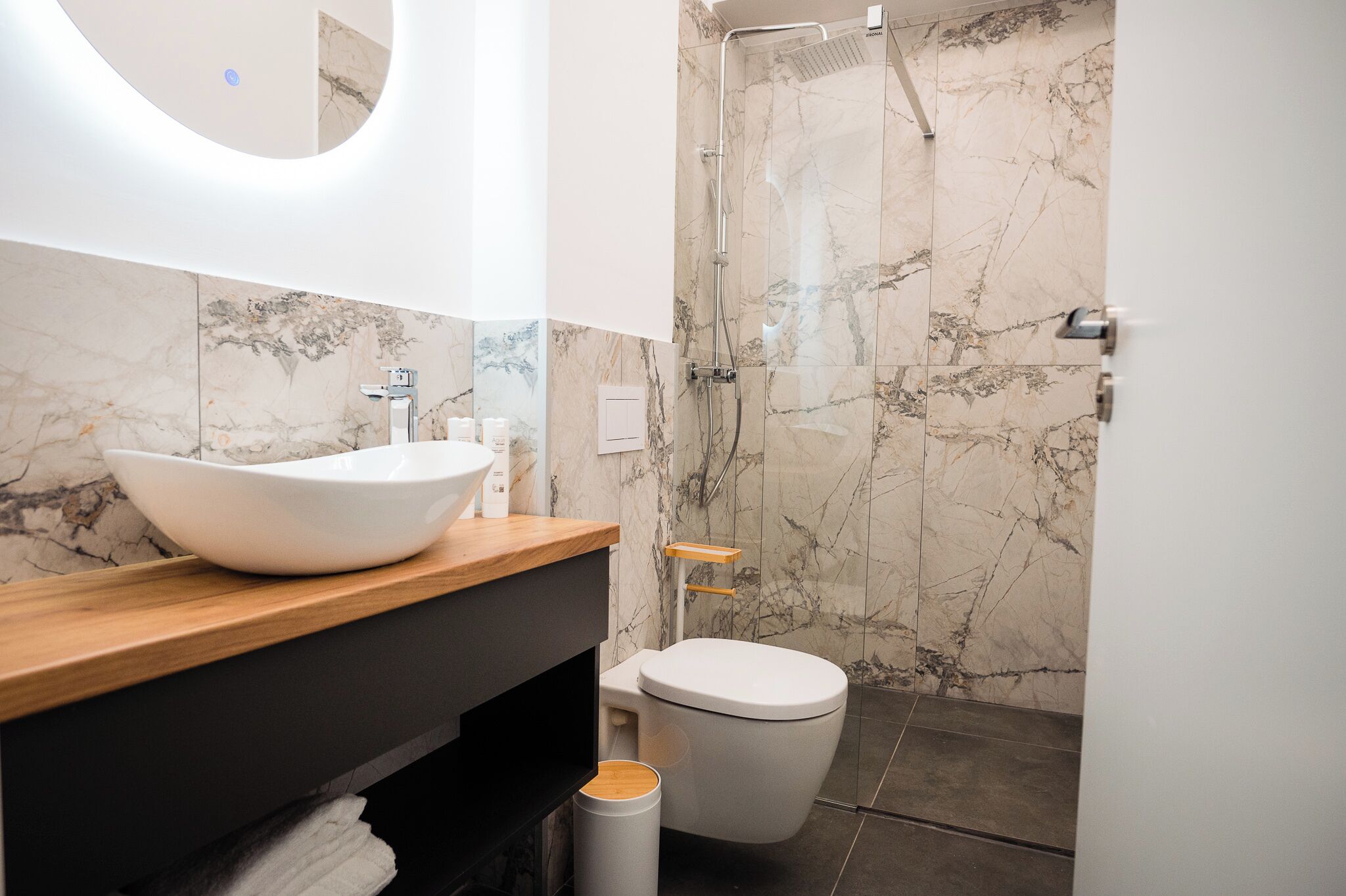 A modern bathroom with a large white sink, a toilet, and a shower area.
