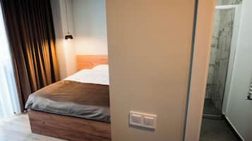 Quarto com cama de madeira, luminária pendente e parede de mármore.