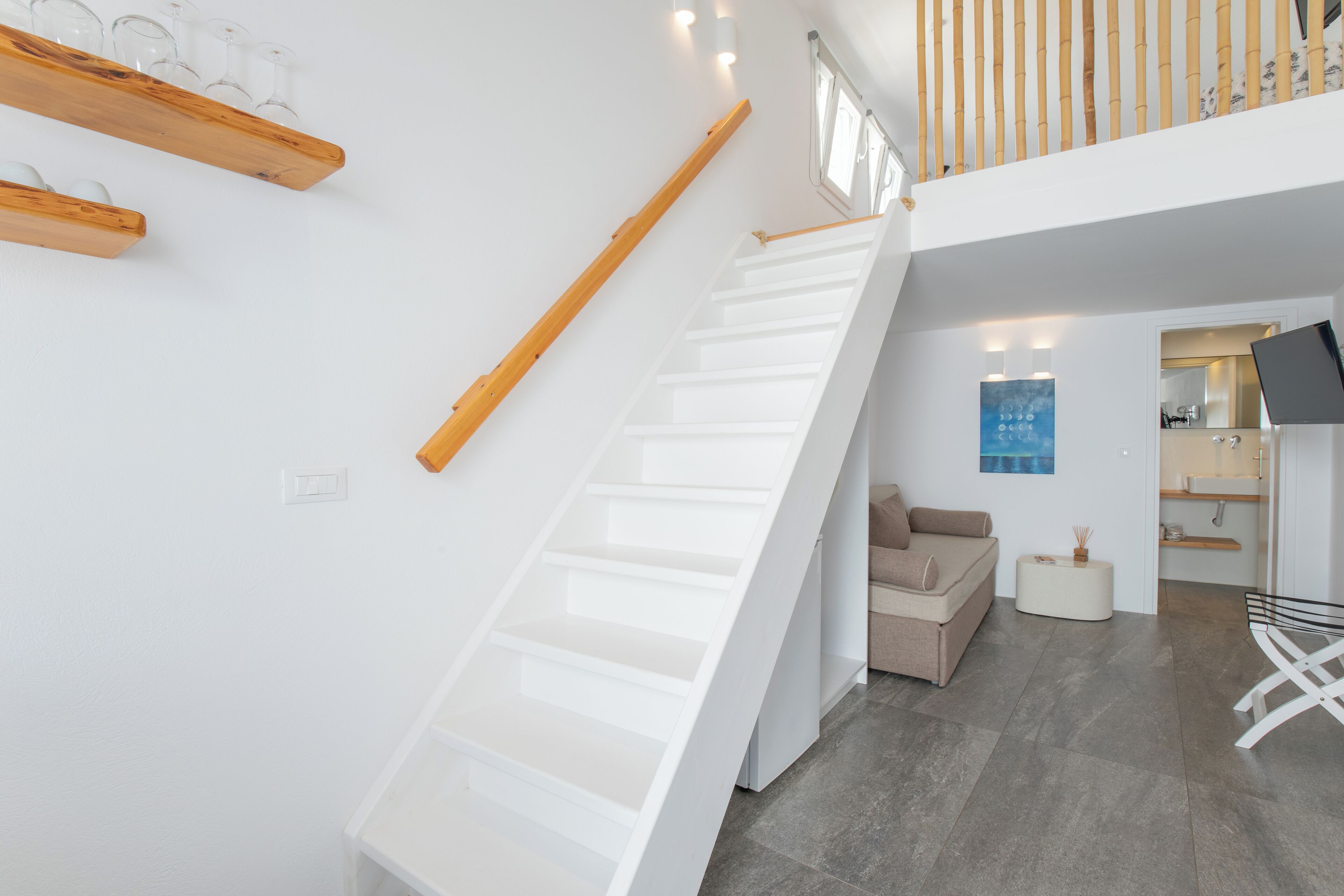 Un intérieur moderne avec un escalier blanc, un canapé et un téléviseur à écran plat.