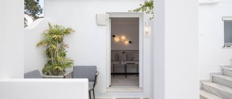 Un interior moderno y minimalista con suelo de piedra, una zona de estar con una planta y un rincón acogedor con una mesa y cojines.