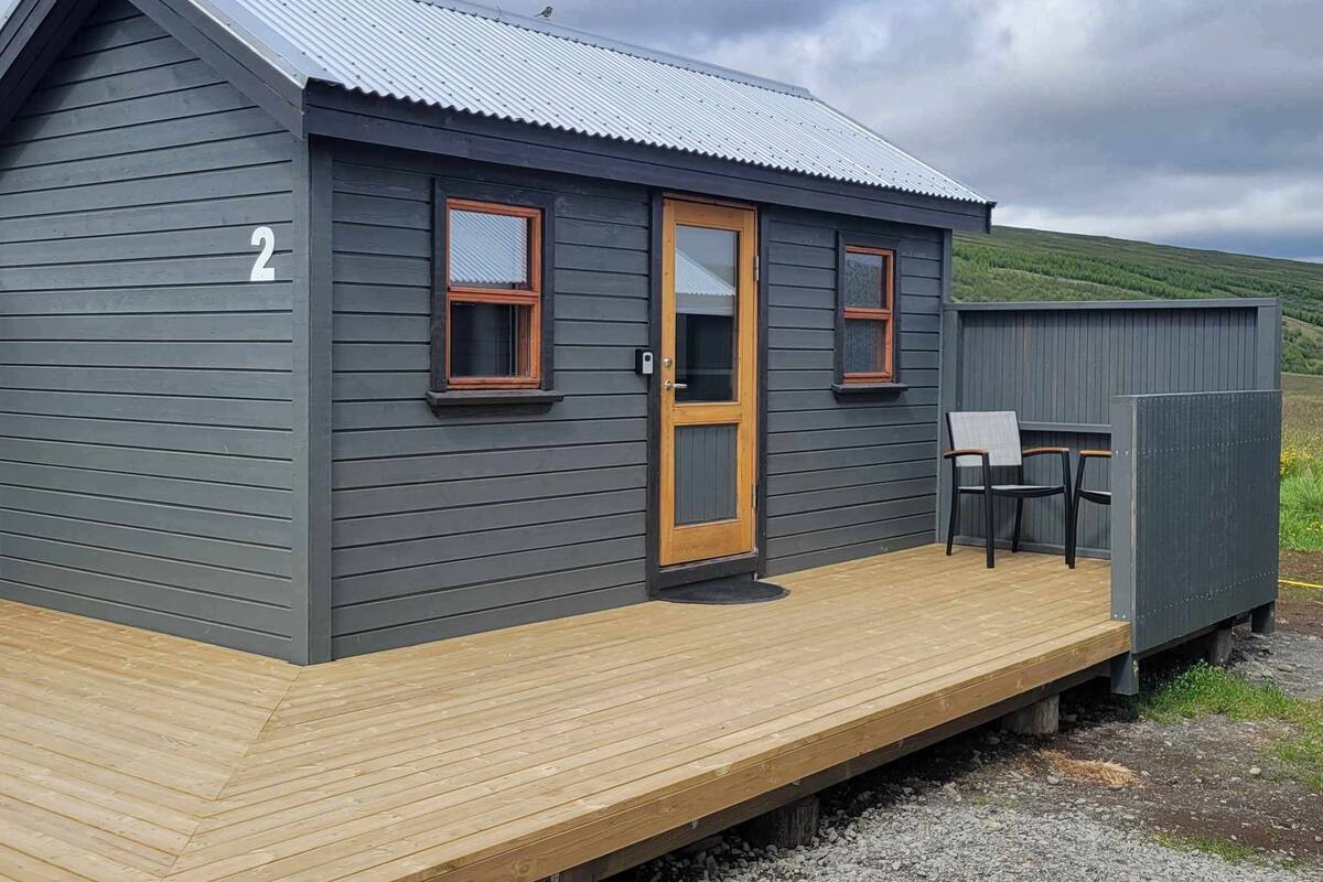 A small cabin with a wooden deck, a door, two windows, and a number '2' on the side.