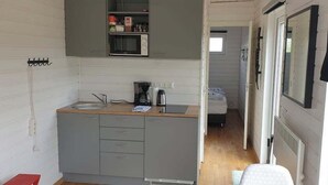 A compact kitchen with a microwave, sink, and a small countertop. A bed is visible in the adjacent room. - Hotel Studlagil Canyon (Egilsstaðir)