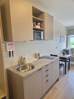Una cocina moderna con microondas integrado, un lavamanos de acero inoxidable y una encimera con una botella de detergente.