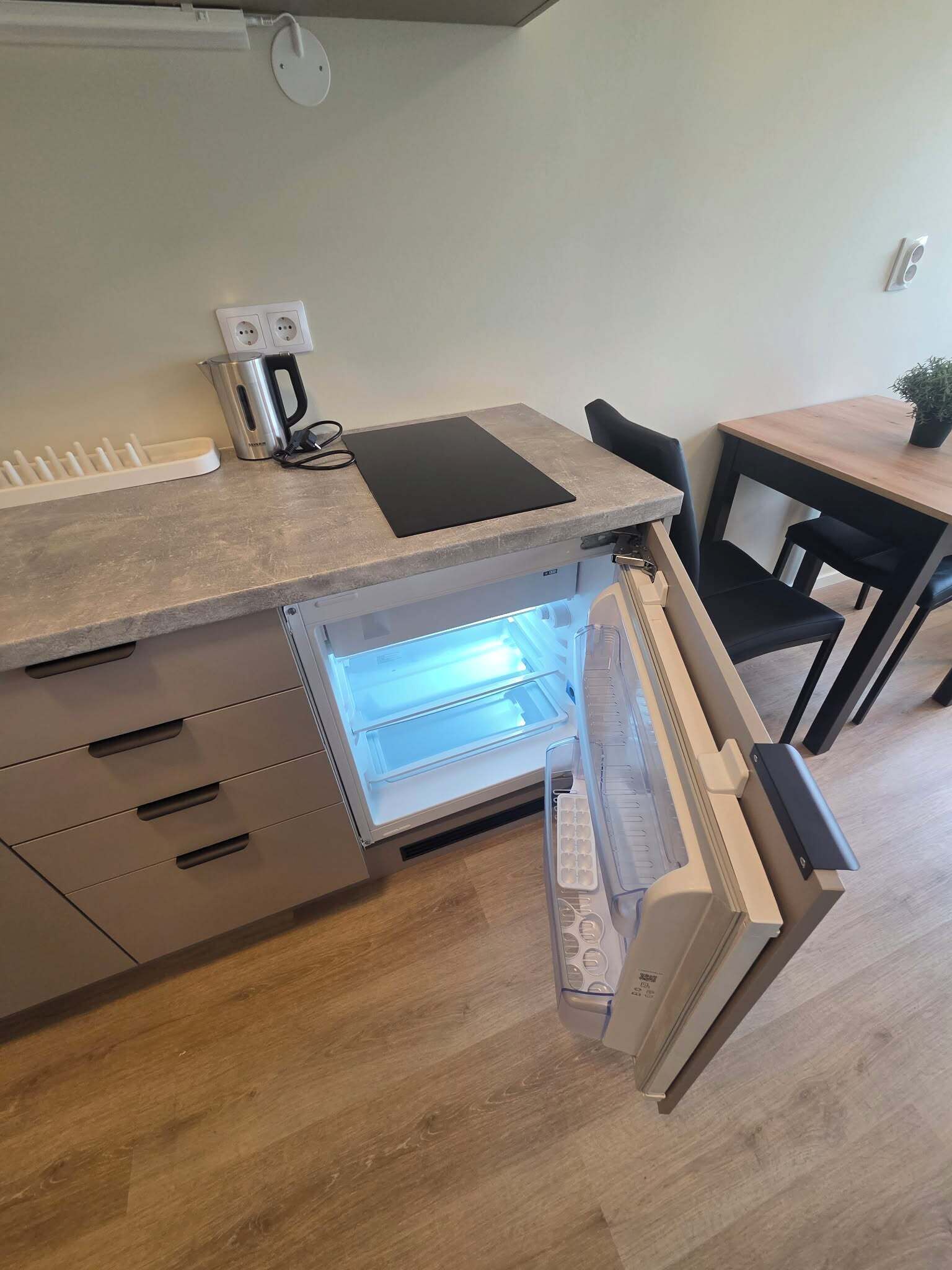A kitchen with a built-in refrigerator, a coffee maker, and a power strip on the countertop.