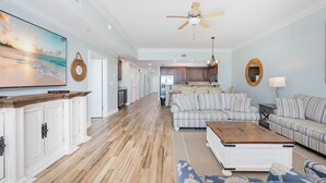 A spacious living room with a large sofa set, a coffee table, and a kitchen in the background. - Phoenix Orange Beach 1602 3 Bedroom Condo (Orange Beach)