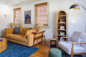 A cozy living room with a sofa, a chair, a bookshelf, and a fireplace. - Near Benning, 2 Kings, 1 Queen, 3 Twins, Room for the Whole Family (Columbus)