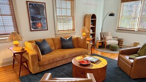 Un salon comprenant un canapé, des fauteuils, une table basse et une bibliothèque.
