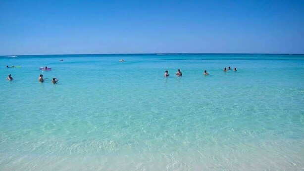 A beach with clear turquoise water and people swimming and relaxing. - Across from the beach! Grand Caribbean West 202 (Destin, Florida)