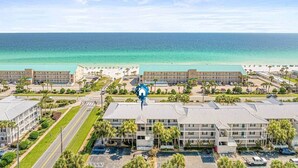 A coastal hotel with multiple buildings, a parking lot, and a view of the ocean. - Across from the beach! Grand Caribbean West 202 (Destin, Florida)