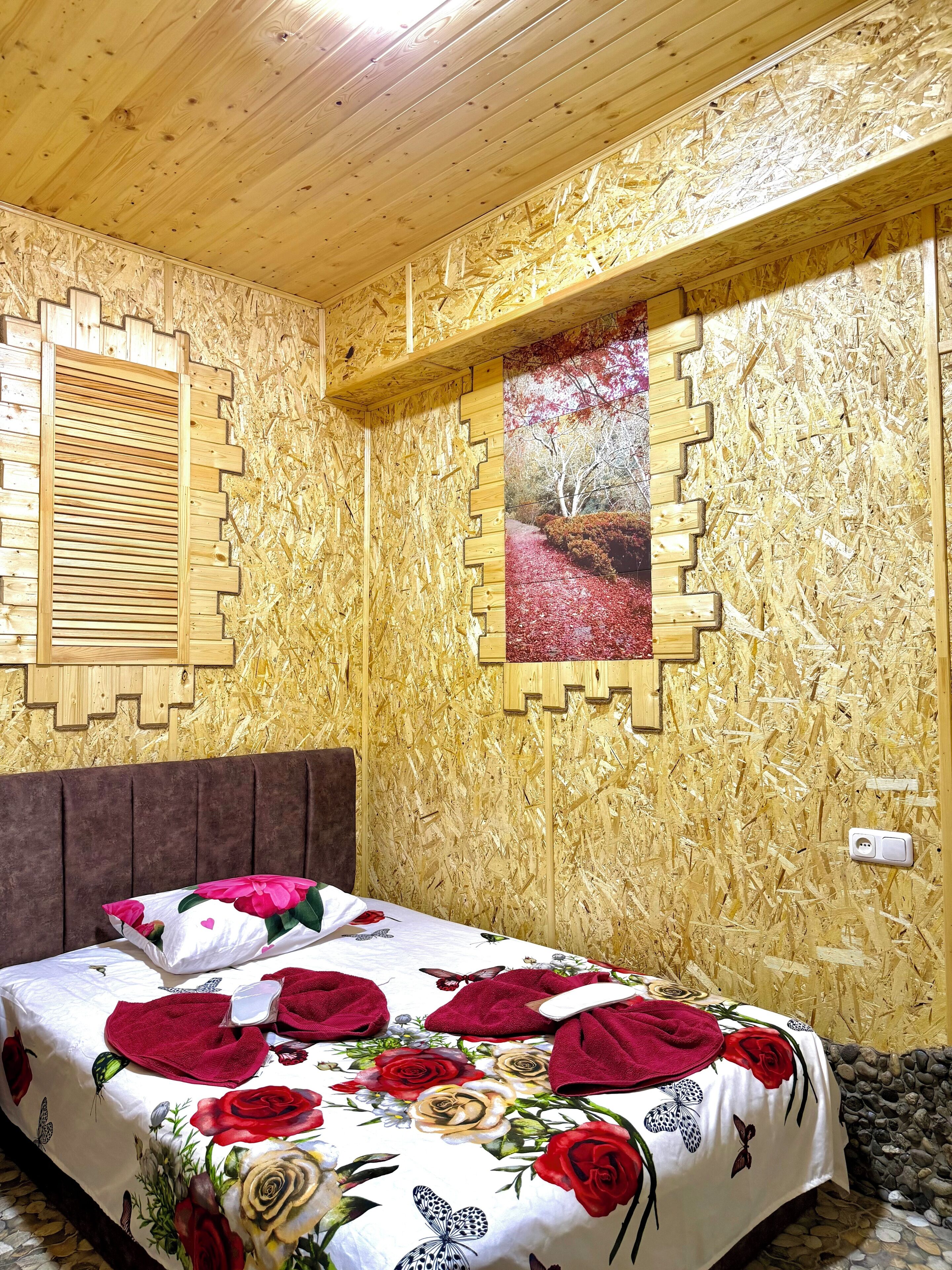 A wooden-paneled room with a bed, a window with blinds, and a wall-mounted picture.