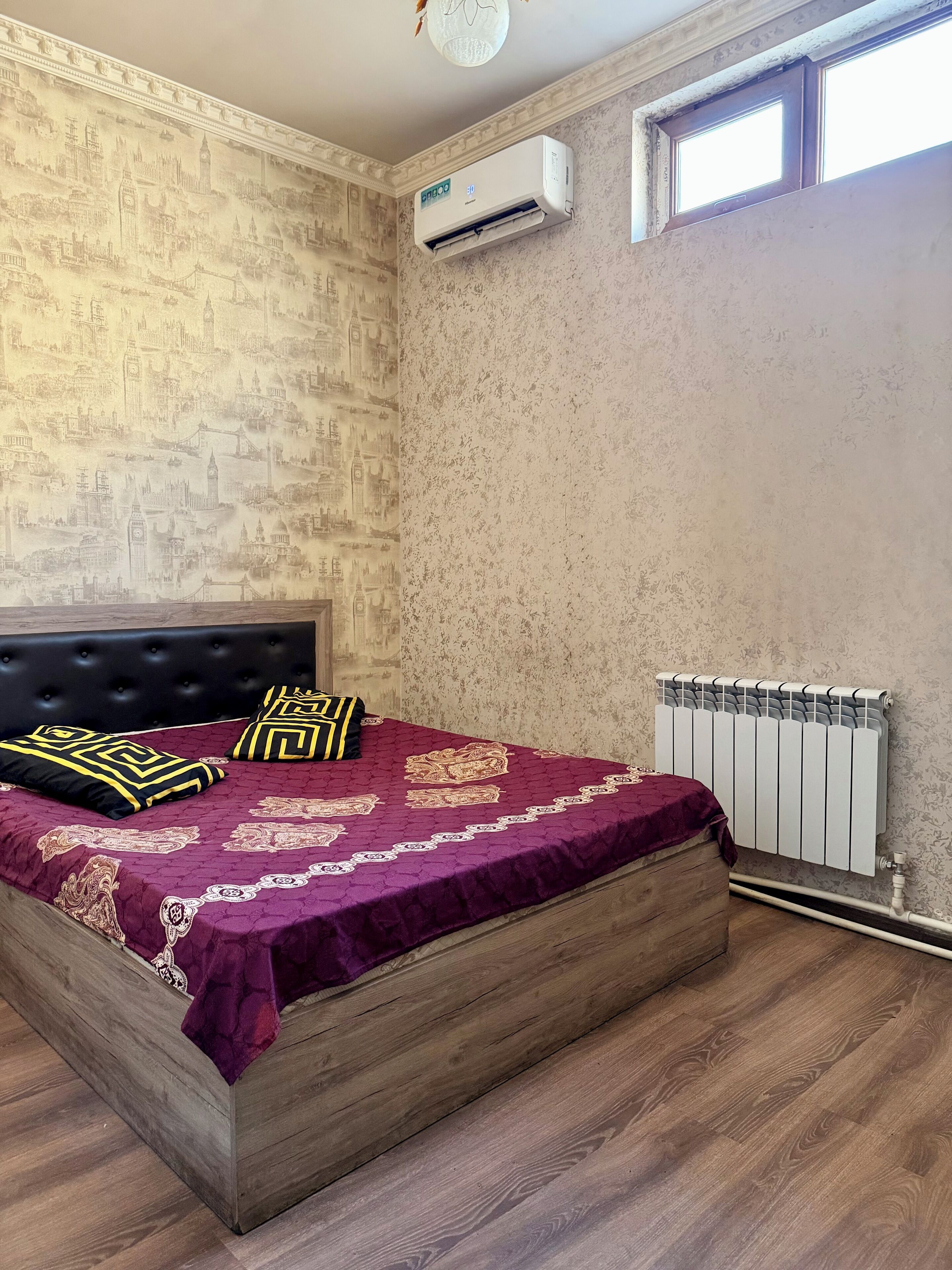 A bedroom with a bed, a radiator, and a window.