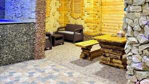 Ein Blockhaus-Interieur mit Steinwänden, Holzbänken und einem Kamin aus Stein.