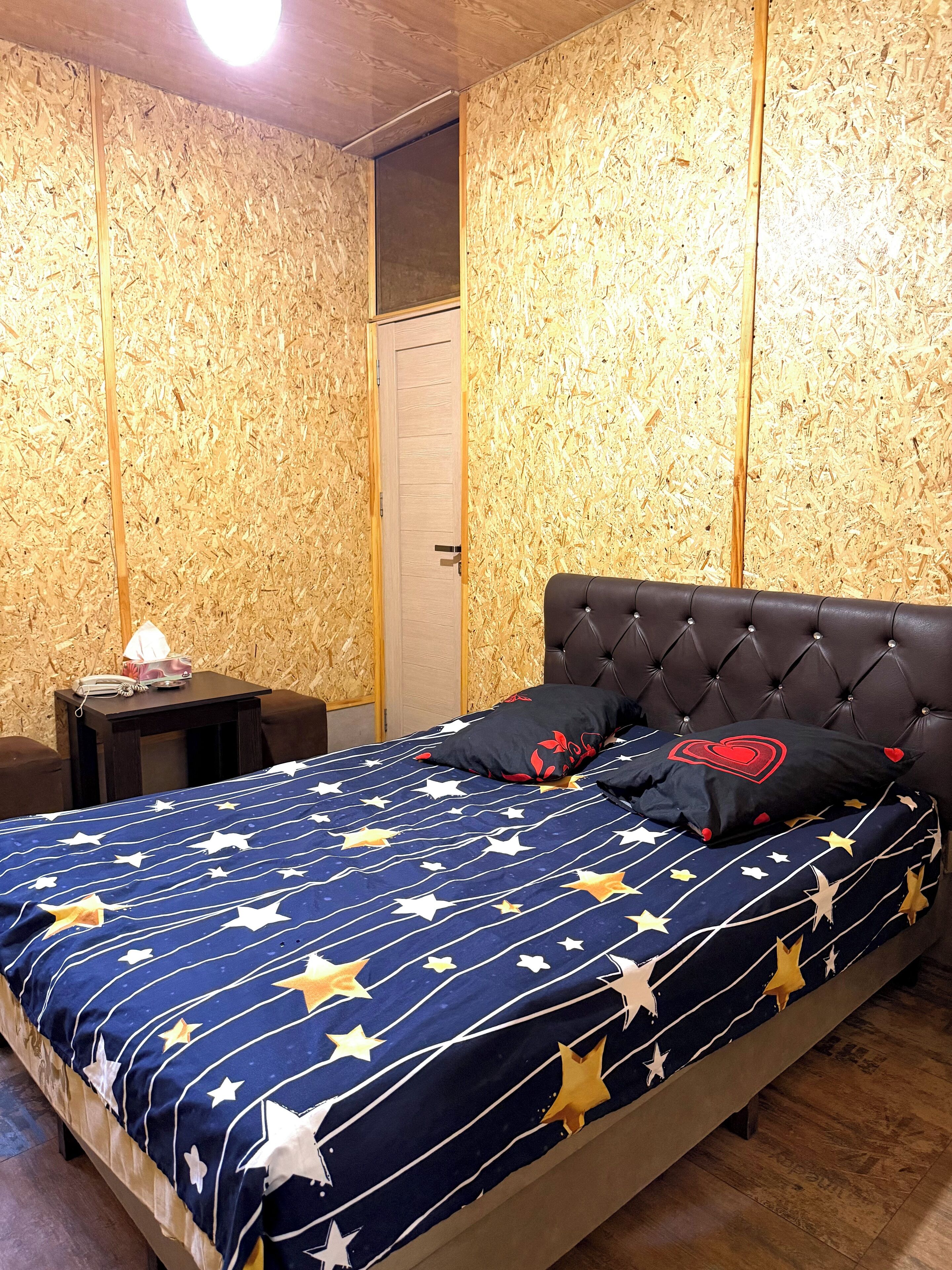 A bedroom with a bed, a nightstand, and a wooden wall.