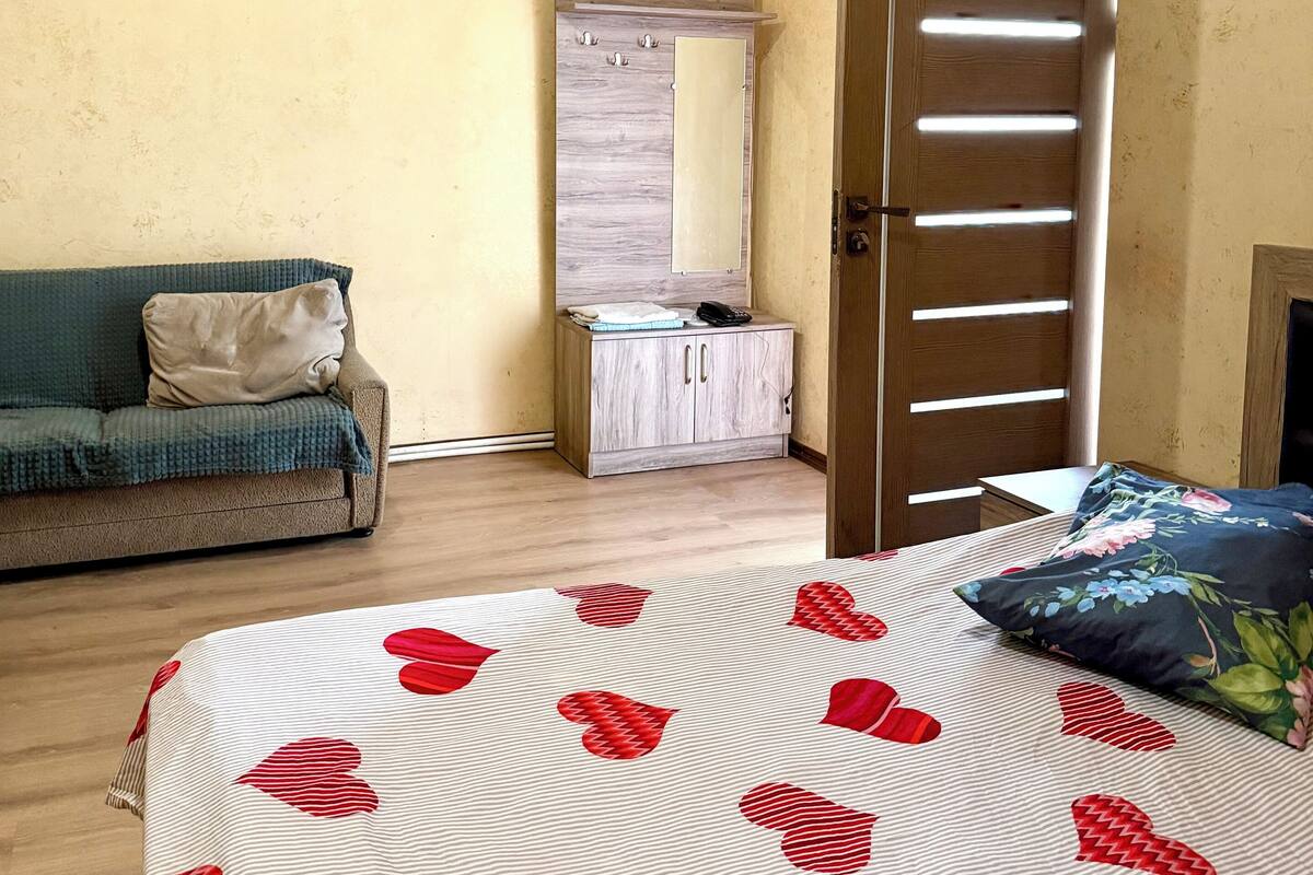 Quarto com cama, sofá, guarda-roupa e ar condicionado.