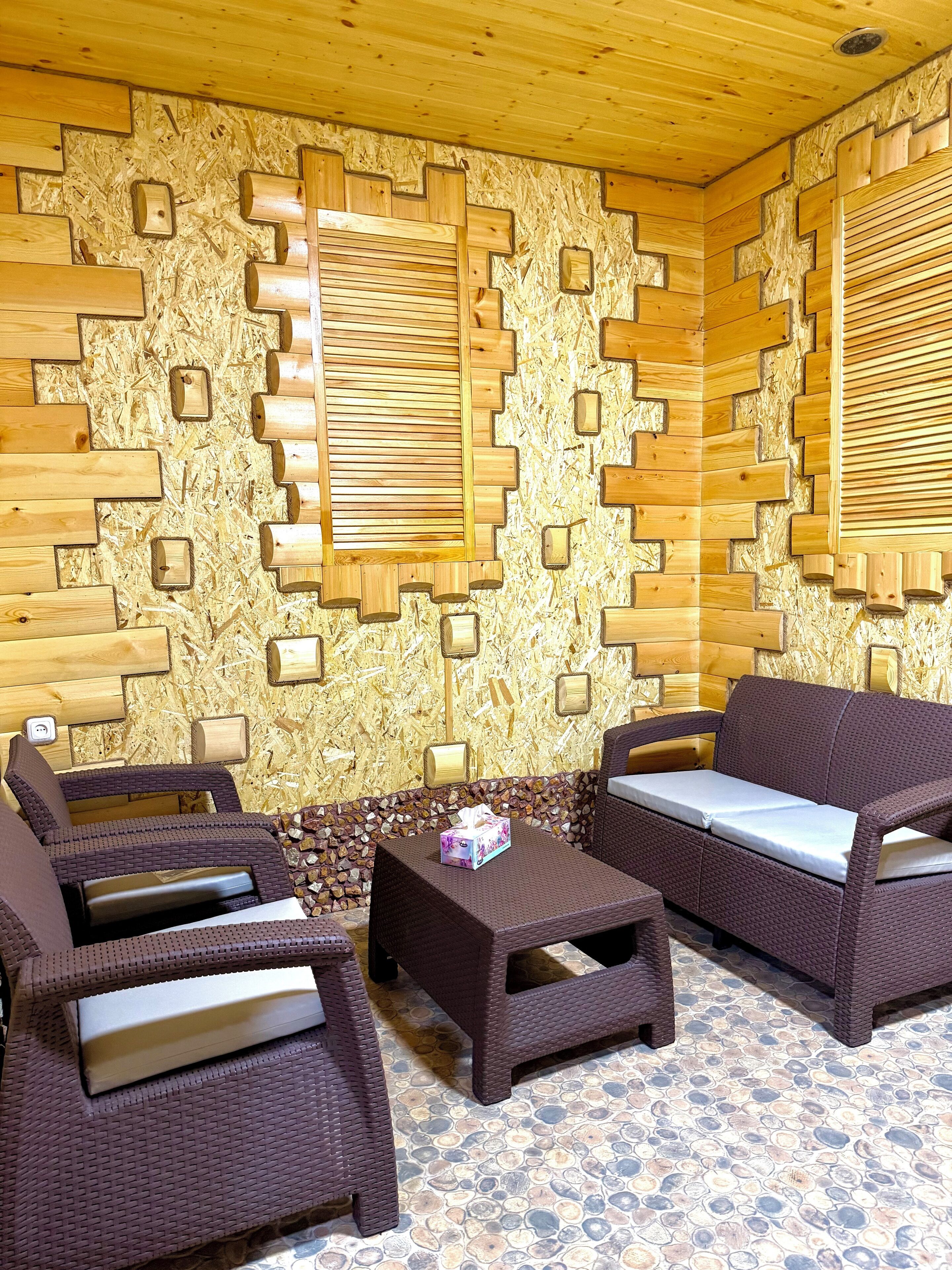 A cozy room with a wooden wall design, wicker furniture, and a tiled floor.