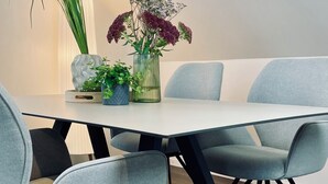 A modern dining area with a rectangular table, grey upholstered chairs, and a variety of potted plants. - Holiday apartment in the Eifel - for those seeking peace and quiet and nature lovers directly on the cycle path (Arzfeld)