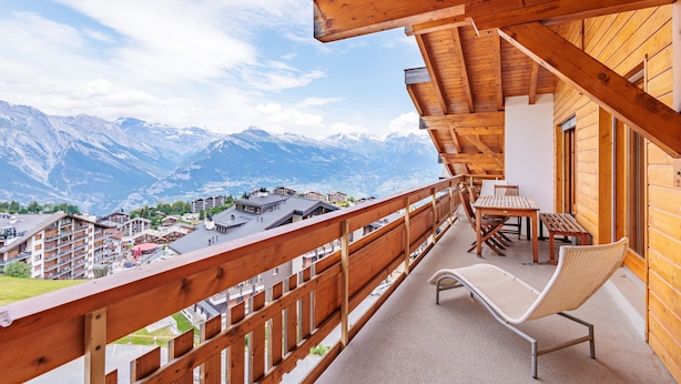 A wooden balcony with a view of snow-capped mountains and a town below. - Victoria II E7 - 10 pers - at the foot of the slopes (Haute-Nendaz)