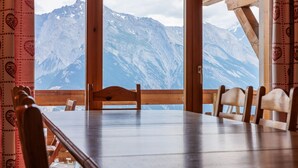 A wooden dining table with chairs, a view of snow-capped mountains through large windows, and a wooden ceiling structure. - Victoria II E7 - 10 pers - at the foot of the slopes (Haute-Nendaz)