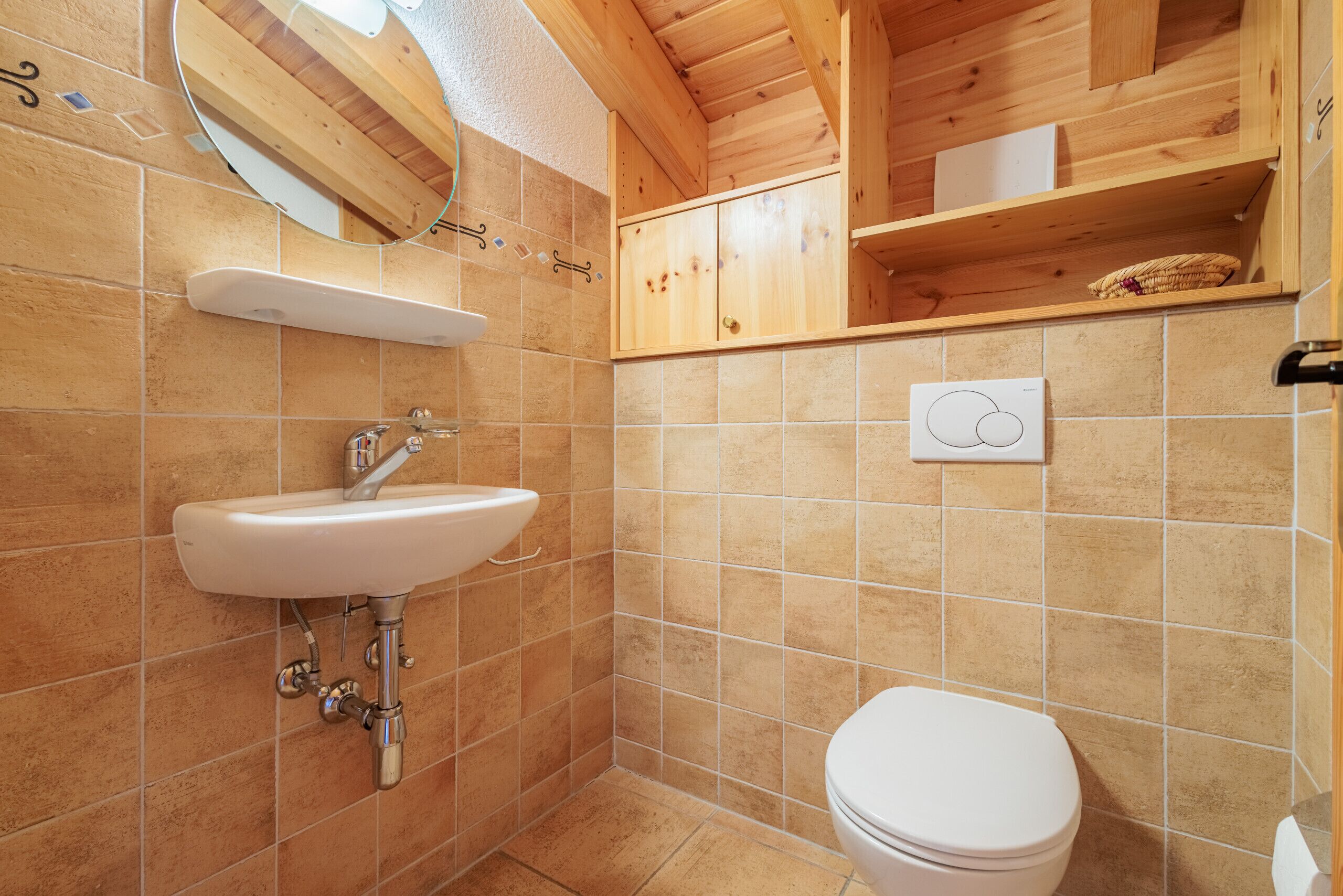 Ein Badezimmer mit einem weißen Waschbecken, einer Toilette und Holzregalen.
