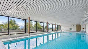A modern indoor swimming pool with clear glass walls, a tiled floor, and a sloped ceiling. - Eden Roc 1 - 4 pers - near the slopes (Haute-Nendaz)