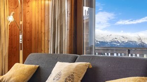 A cozy room with a sofa, pillows, and a view of snow-capped mountains through a large window. - Eden Roc 1 - 4 pers - near the slopes (Haute-Nendaz)