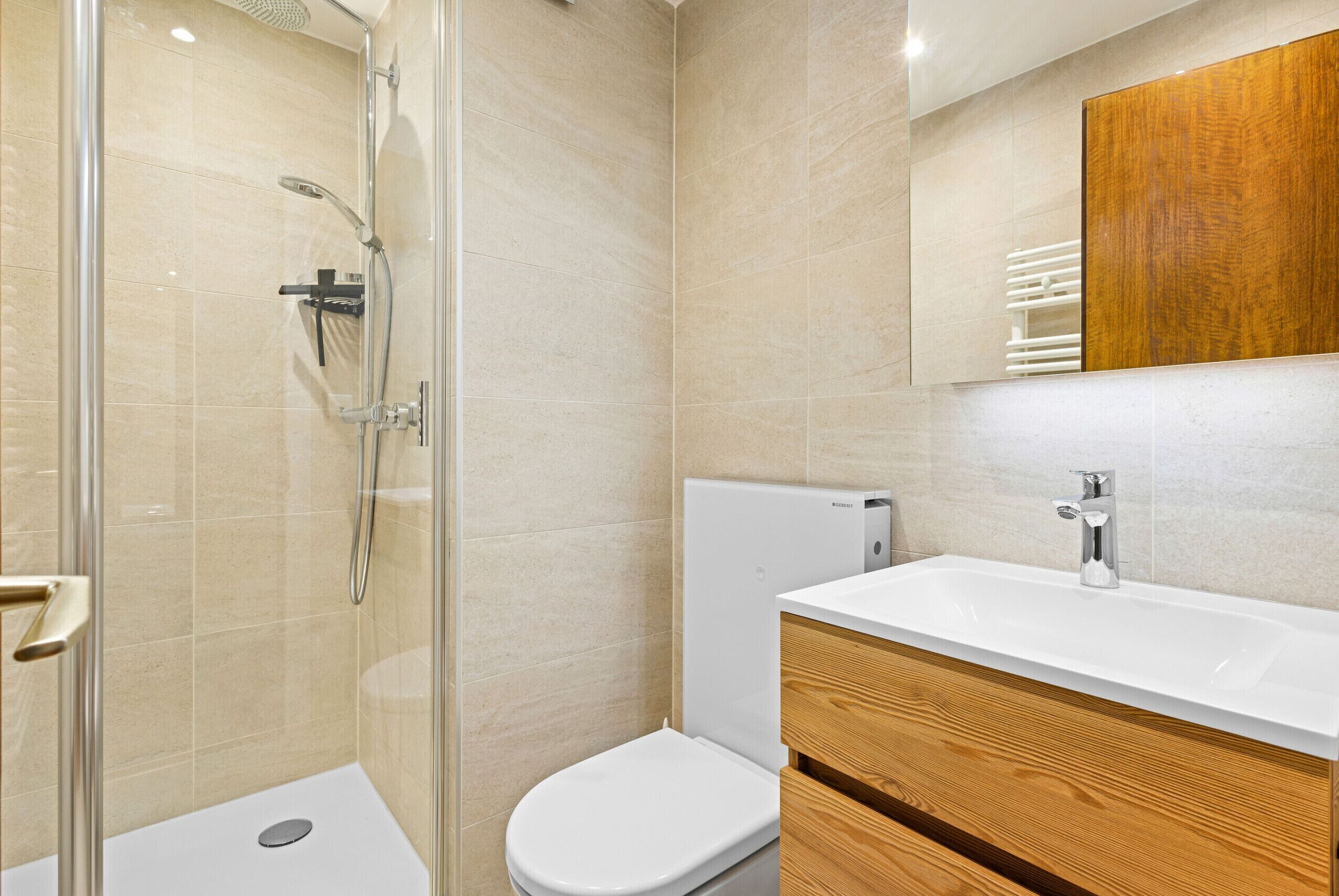 Une salle de bain moderne avec une douche à parois de verre, des toilettes blanches et un meuble-lavabo en bois avec un vasque blanche.